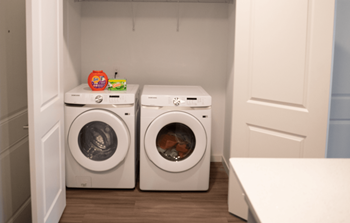 Two white front loading washing machines in a small laundry room.